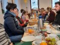 eine lange reichlich gedeckte Fr&uuml;hst&uuml;cks-Tafel mit viele Menschen - 1. Fr&uuml;hst&uuml;cks- Gottesdienst am 25.01.2026 in Triebel