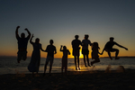 Ferienglueck - Silhouette springender Menschen vor Sonnenuntergang am Stand