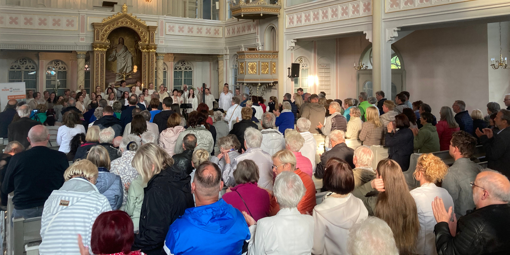 Gospel zu Pfingsten - Zuschauer und Gospelchor in der St. Georg Kirche in Schöneck