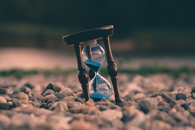 halbleere Sanduhr auf Erdboden in Natur - "Halbzeit, Pause, Johannis"